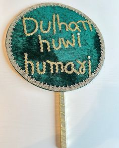 a green and gold hand fan with the words durham town mumbai on it's side