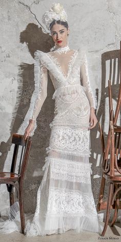 a woman standing next to a chair in front of a wall wearing a white dress