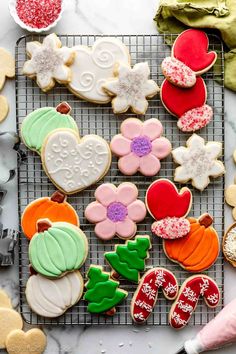 decorated cookies are on a cooling rack next to other cookie ingredients and decorations for christmas