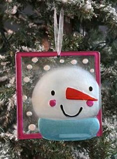 a snowman ornament hanging on a christmas tree in the shape of a square