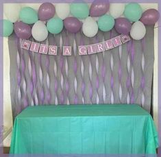 there is a green table with purple and white balloons