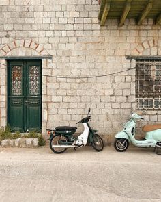 two mopeds parked next to each other in front of a brick building