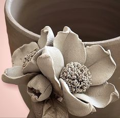 a close up of a vase with a flower on it's side and a pink background