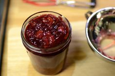 a glass jar filled with cranberry sauce next to a metal bowl