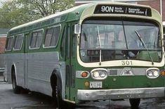 a green and white bus parked in front of a brick building on a rainy day