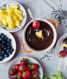 fruit and chocolate fondant on plates with spoons next to them, including strawberries