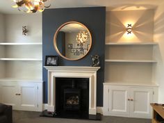 a living room filled with furniture and a fire place in front of a round mirror