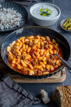 a skillet filled with pasta and meat on top of a wooden cutting board next to other dishes