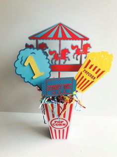 a popcorn bucket filled with different types of candy and paper cutouts on top of it