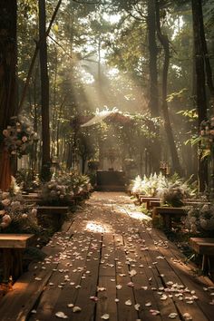 an outdoor ceremony with flowers on the ground and benches in the foreground, surrounded by trees