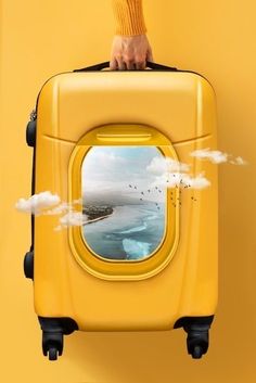 a person holding a yellow piece of luggage with an image of the ocean on it