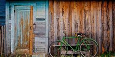 a green bike parked next to a wooden building