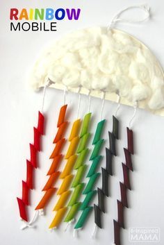 several different colored toothpicks are hanging on a white wall with clouds in the background