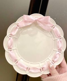 a person holding a white plate with pink bows on it