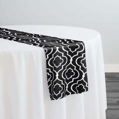 a black and white table runner on top of a round table with an elegant design