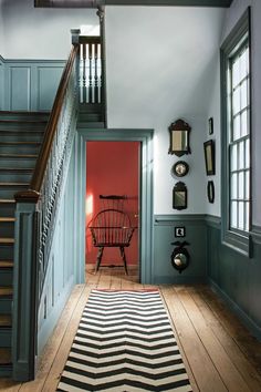 a hallway with blue walls and wooden floors has a striped rug on the hardwood floor