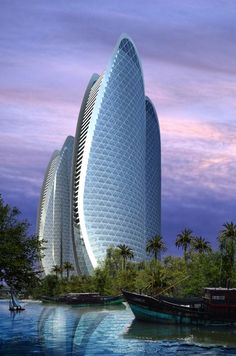 two boats are in the water next to a tall building that is surrounded by palm trees