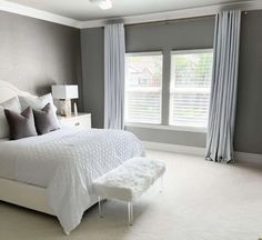 a large white bed sitting in a bedroom next to two windows