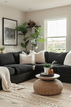 a living room filled with black couches and white pillows on top of a rug