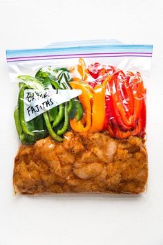 a bag filled with chicken and peppers on top of a white table next to a knife