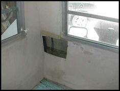 the corner of a room with a hole in the wall and a window on the other side