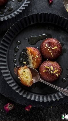 three pastries on a black plate with spoons