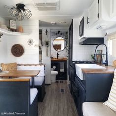 the interior of an rv with wood flooring and white walls, black cabinets, and wooden counter tops