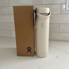 a white water bottle sitting next to a cardboard box on a counter with the lid open