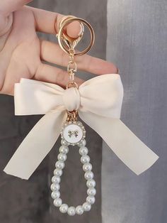 a person is holding a key chain with a bow on it and pearls around the neck