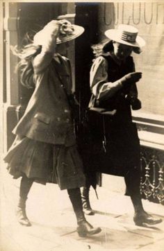 an old black and white photo of two women in hats looking at their cell phones