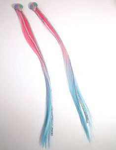 two long blue and pink hair are on a white surface, one has beads in it