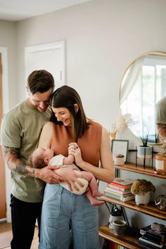 a man and woman holding a baby in their arms