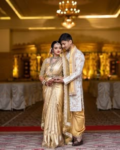 a man and woman standing next to each other in front of a chandelier