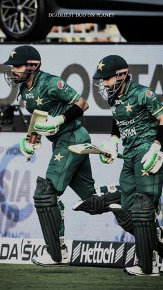 two men in green uniforms are playing cricket