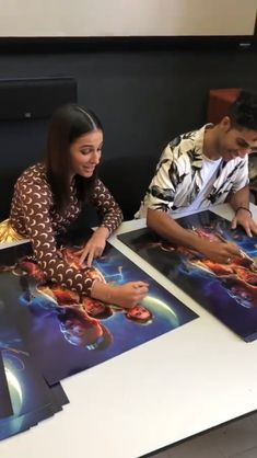 two people sitting at a table with pictures on it