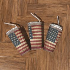 three cups with straws in them are on the floor and one has an american flag painted on it