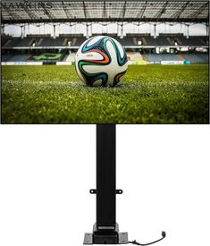 a soccer ball sitting on top of a green field next to a tv monitor screen