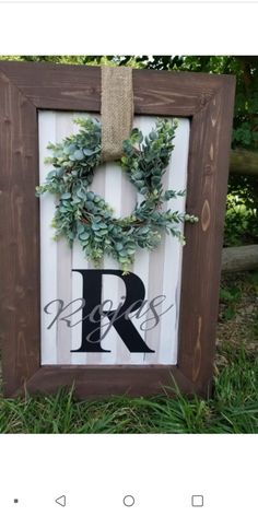 a wooden frame with a wreath on it and the letter r painted in black ink