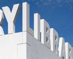 there is a large white sign that says library on the side of a building with blue skies in the background