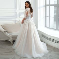 a woman in a wedding dress standing by a window