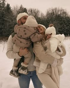 a man and woman are walking in the snow with their baby girl, who is wearing a hat