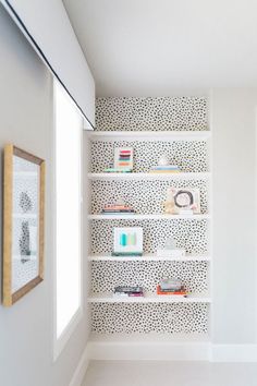 there is a shelf with books on it in the corner next to a wall mounted mirror