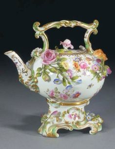 a tea pot with flowers painted on the side and gold trimming around the top