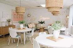 a white table and chairs in a room with flowers on the wall behind it,