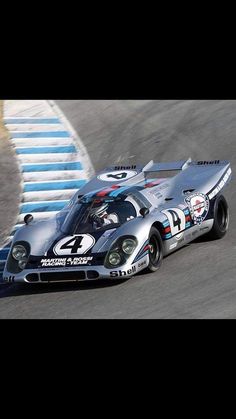 a silver race car driving down a track with the number 4 on it's side