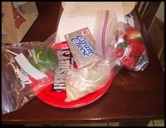 some food is sitting on a red plate with plastic wrap around it and two bags of chips