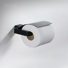 a roll of toilet paper hanging on the wall next to a black and white holder