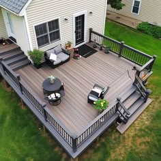 an aerial view of a deck with chairs and tables in the grass next to a house