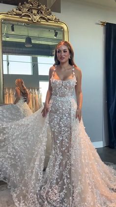 a woman standing in front of a mirror wearing a wedding dress with flowers on it