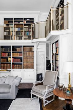 a living room filled with furniture and bookshelves next to a stair case full of books